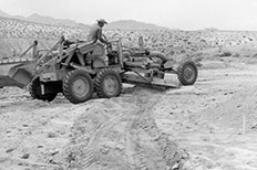 Man operating a grader in the desert.