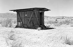 Small wooden building with sign that says Men on it.