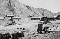 Several small buildings up against a mountain.