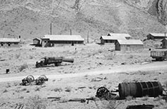 Several small buildings up against a mountain.