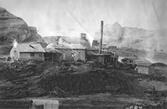 Grouping of buildings with a smoke stack on one.