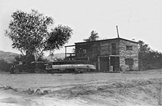 Two story wooden building with truck towing large boat out front.