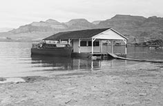 Floating building with sloped porch and boat tied to it.