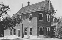 Corner view of a large brick house with a slanted roof.