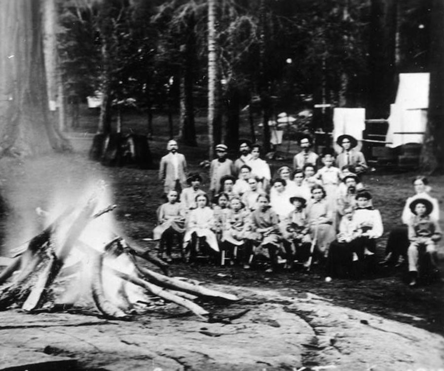 A historic photo of people arounf a large campfire