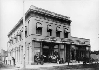 Two-story storefront with wares advertised along the sidewalk.