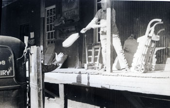 Men throwing bags of flour into a truckbed from a loading dock.