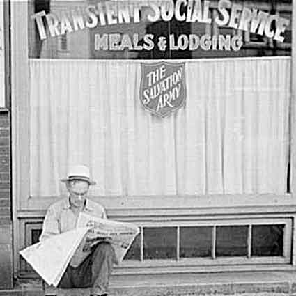Man reads a newspaper in front of Salvation Army building