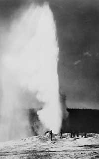 Black and white photo of people watching a geyser erupt