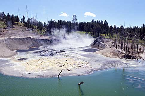 A slurry of mud and sand is surrounded by blue water at Mud Volcano