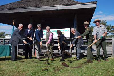 Groundbreaking participants sling their shovels of dirt in front of the old ferry terminal building.