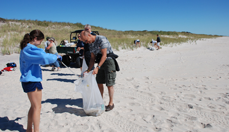 Volunteers on the beach place debris in garbage bags.