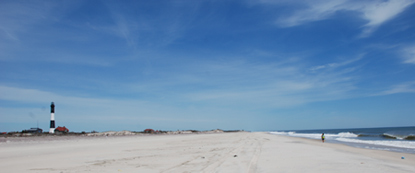 Wide beach in front of Fire Island Lighthouse with lone beachcomber