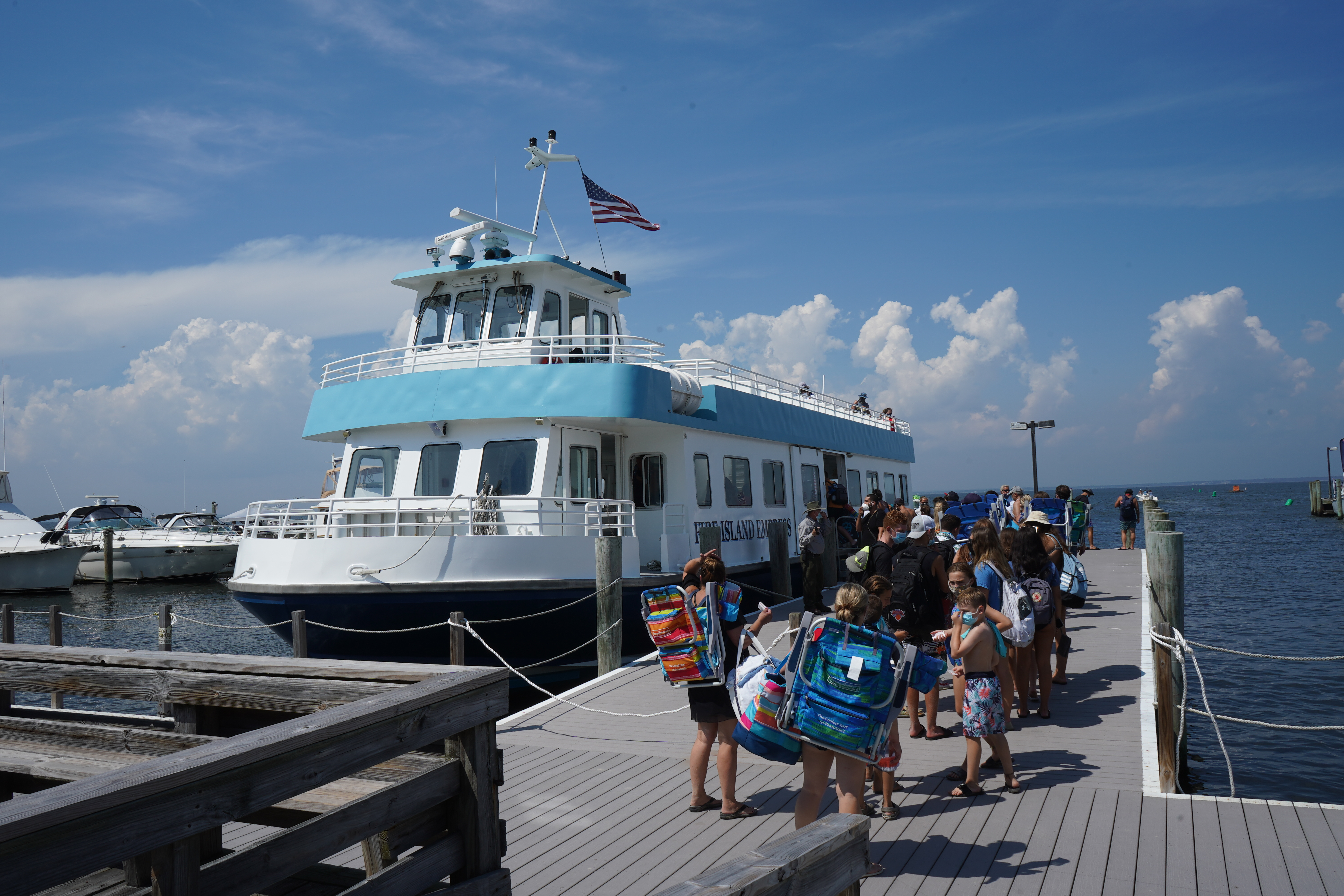 A large blue and white ferry loads passengers at a marina