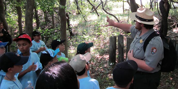 A park ranger points to trees in the Sunken Forest on a tour with school children.