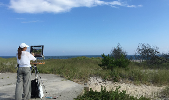 A woman paints en plein air by the water.