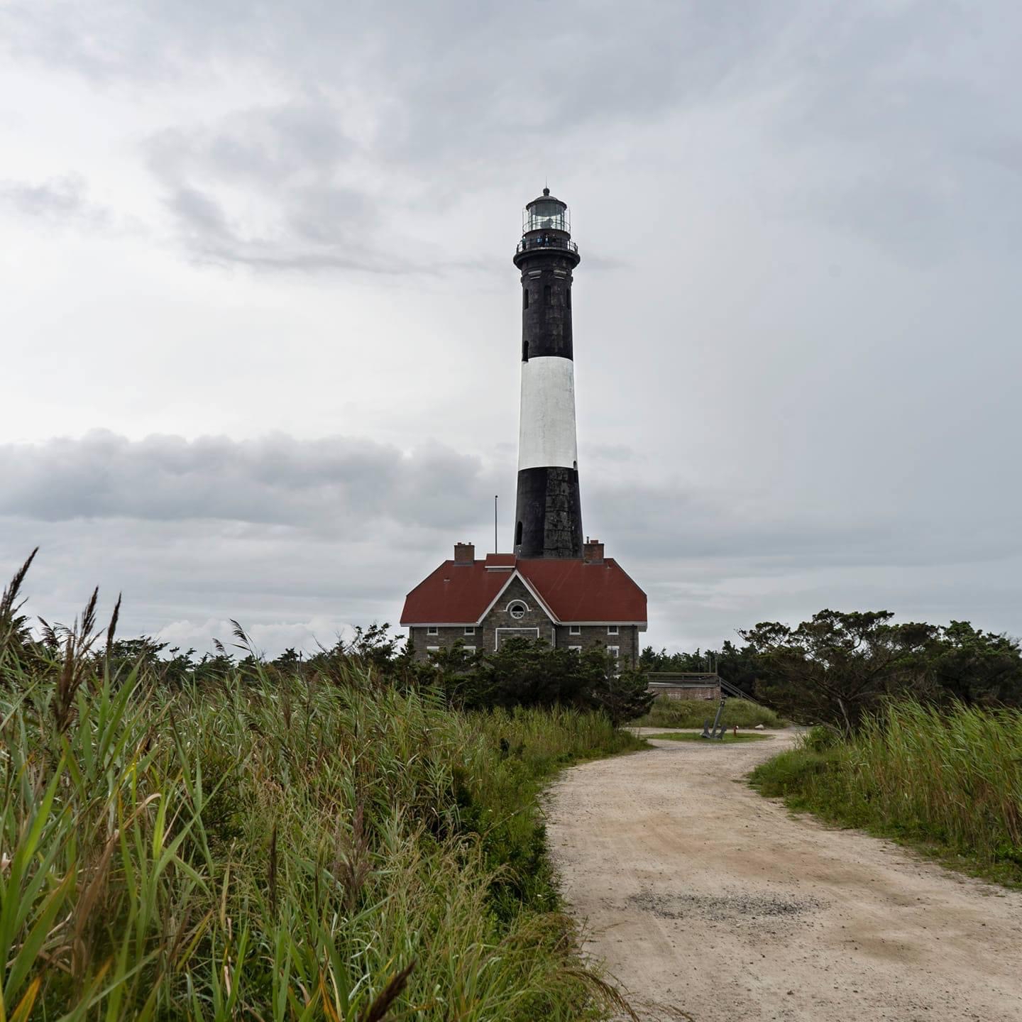 Photo of Fire Island Lighthouse centered in image with gravel road on right side