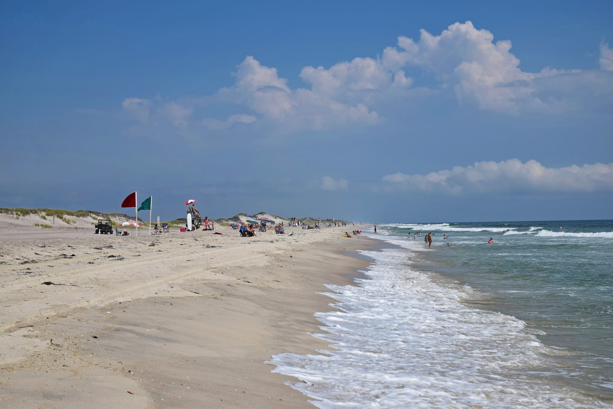 Lifeguards, sunbathers, and swimmers at an ocean beach in summer.