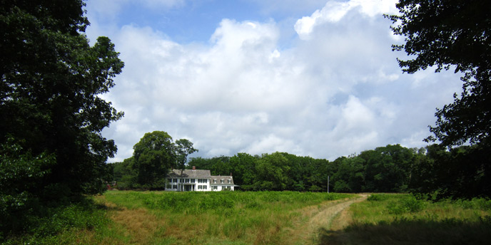 View of historic Old Mastic House across green fields.