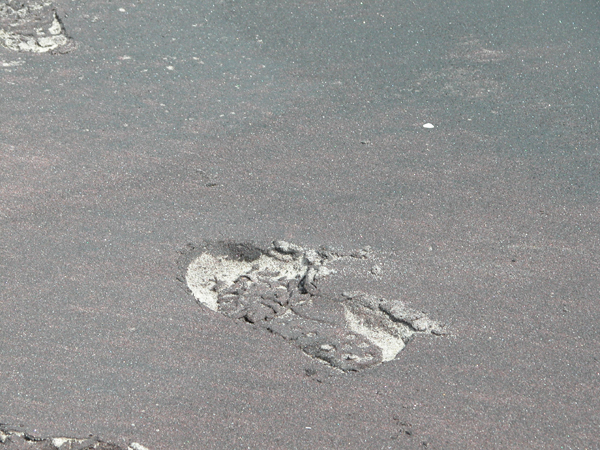Footprint in reddish sand.