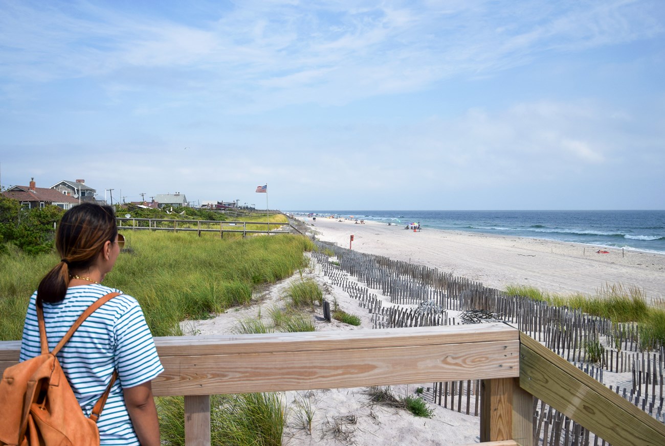 A person looks down a beach with beach houses and beachgoers in view.