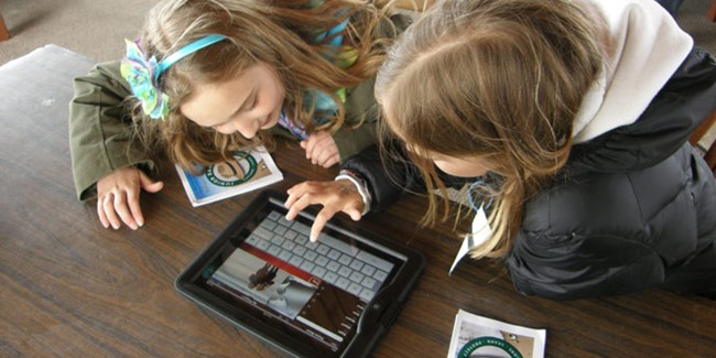 Two young visitors use an iPad to explore the seashore.
