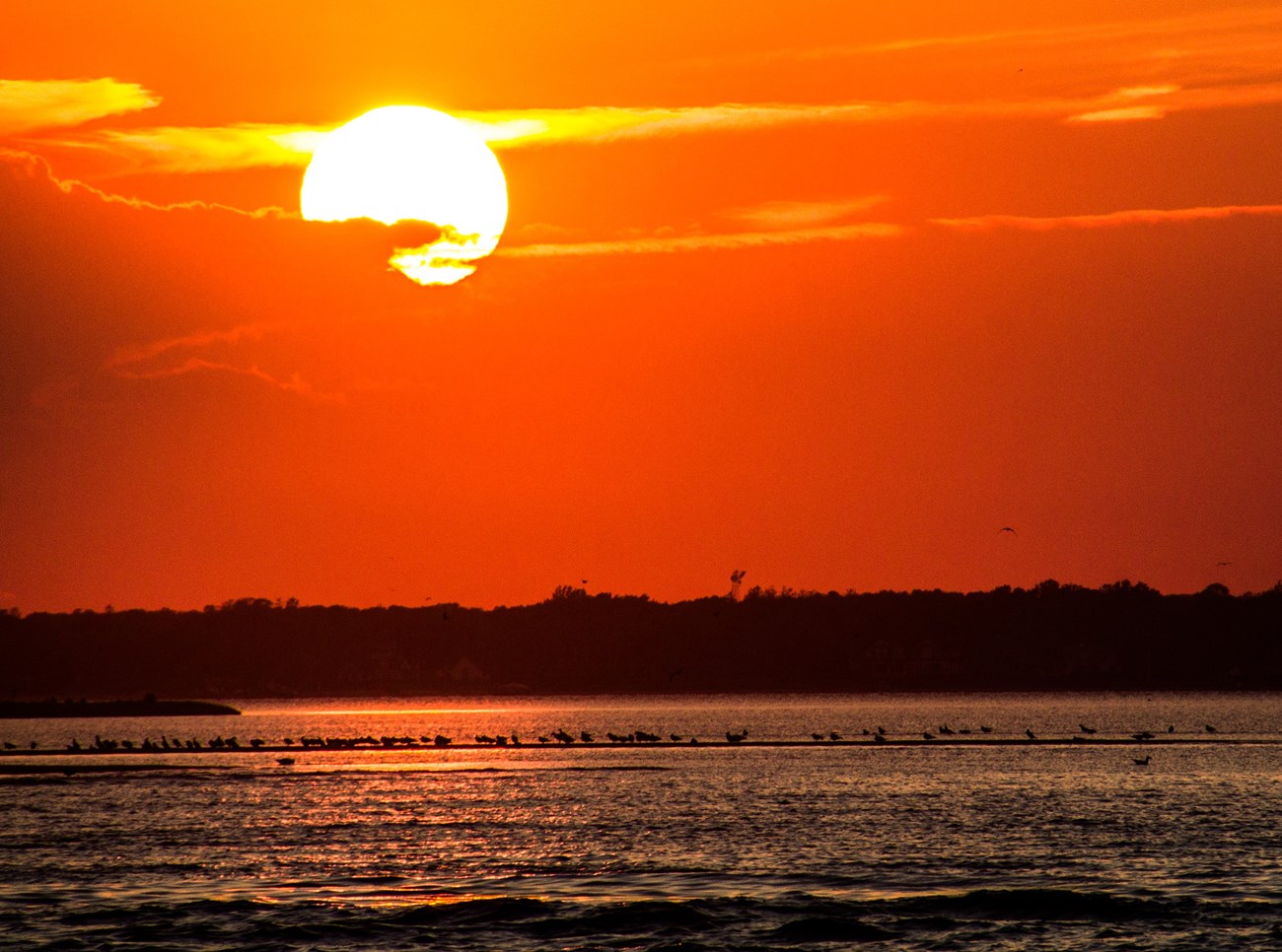 Beach sunset with water reflecting in the foreground.