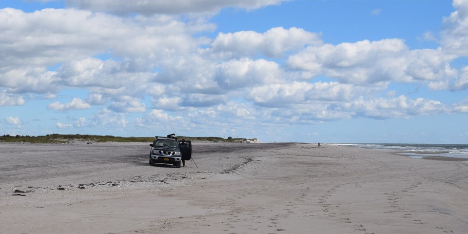 A truck drives down the beach.