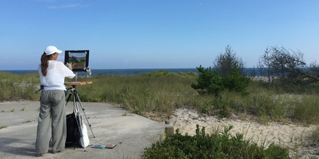 A plein air painter depicts the seashore.