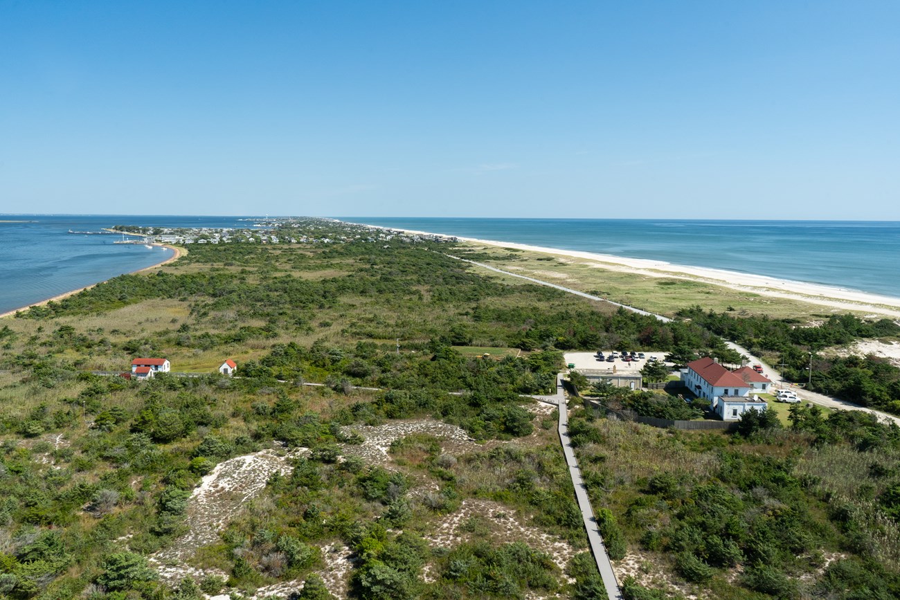 An aerial view showing a narrow island with ocean and bay.