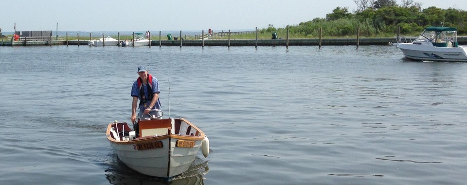 A man operates a small boat in a marina