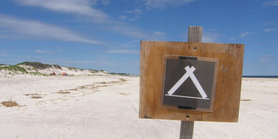 A campground sign on the beach.
