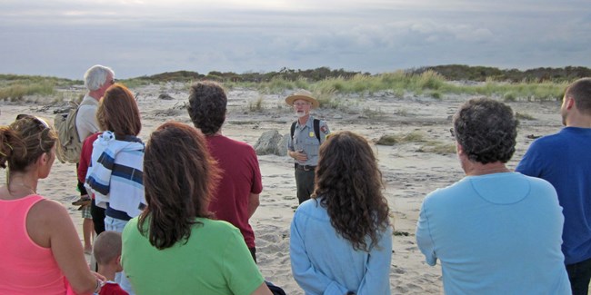 A park ranger leads a group on a hike to the breach at Old Inlet