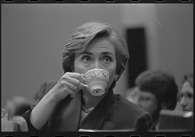 First Lady Hillary Clinton head-and-shoulders portrait, sipping from a teacup during her presentation at a congressional hearing on health care reform.