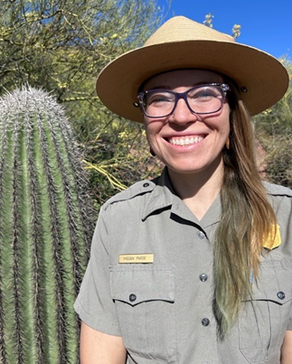 Megan Parde Head and shoulders photograph of Megan Parde wearing a full park uniform and flat hat with a cactus to her right hand side