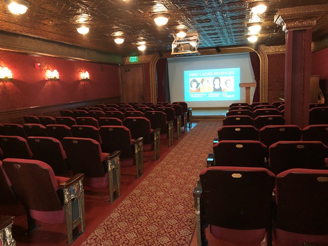 movie theater with red chairs and a projection screen