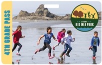 2016 4th Grade Pass with five children running on beach with large rocks in background