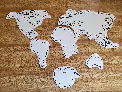 Paper cutouts of the seven continents arranged on a table as they are on a modern map.