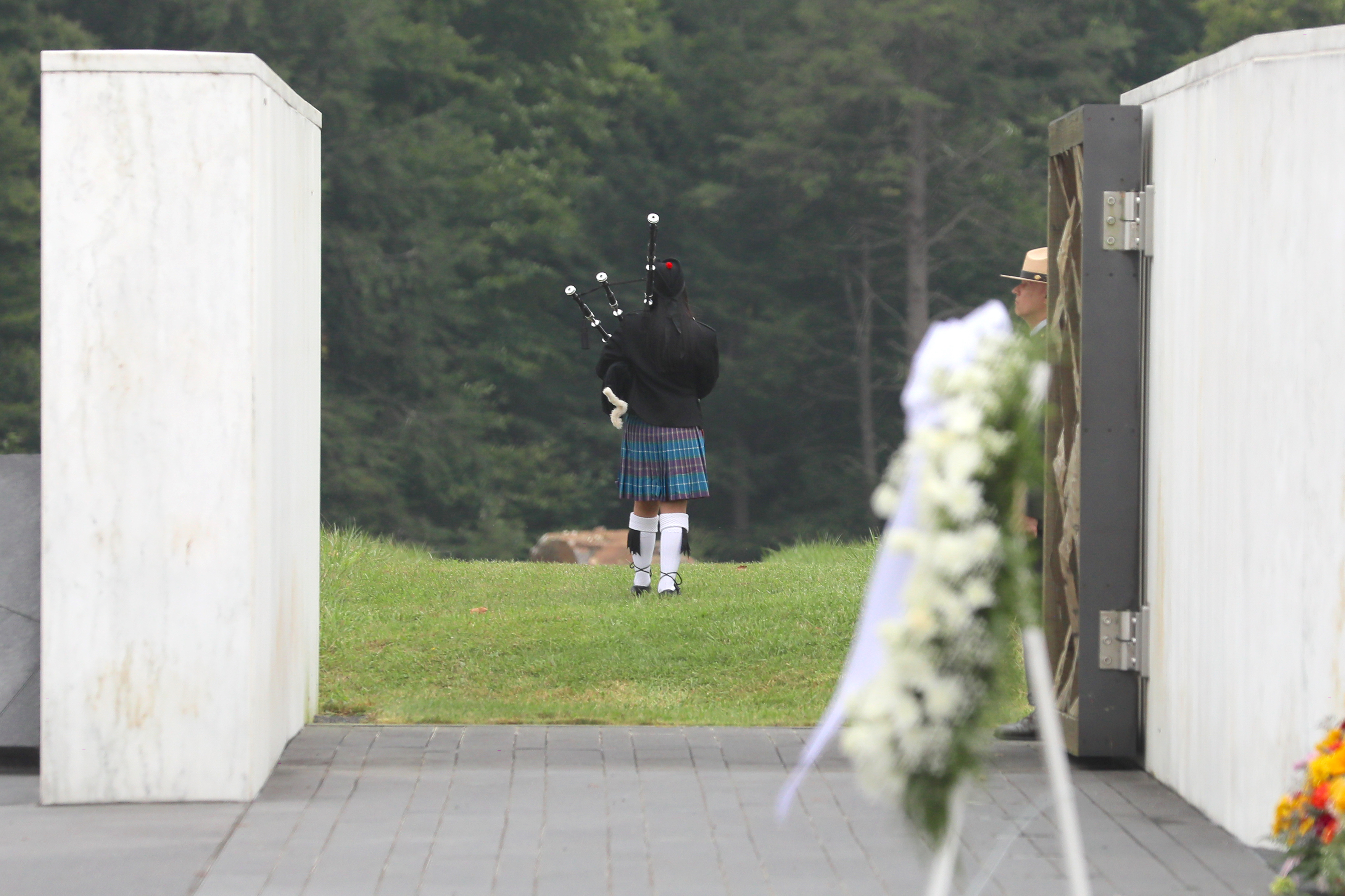 Bagpiper walks out toward the boulder indicating the Flight 93 crash site