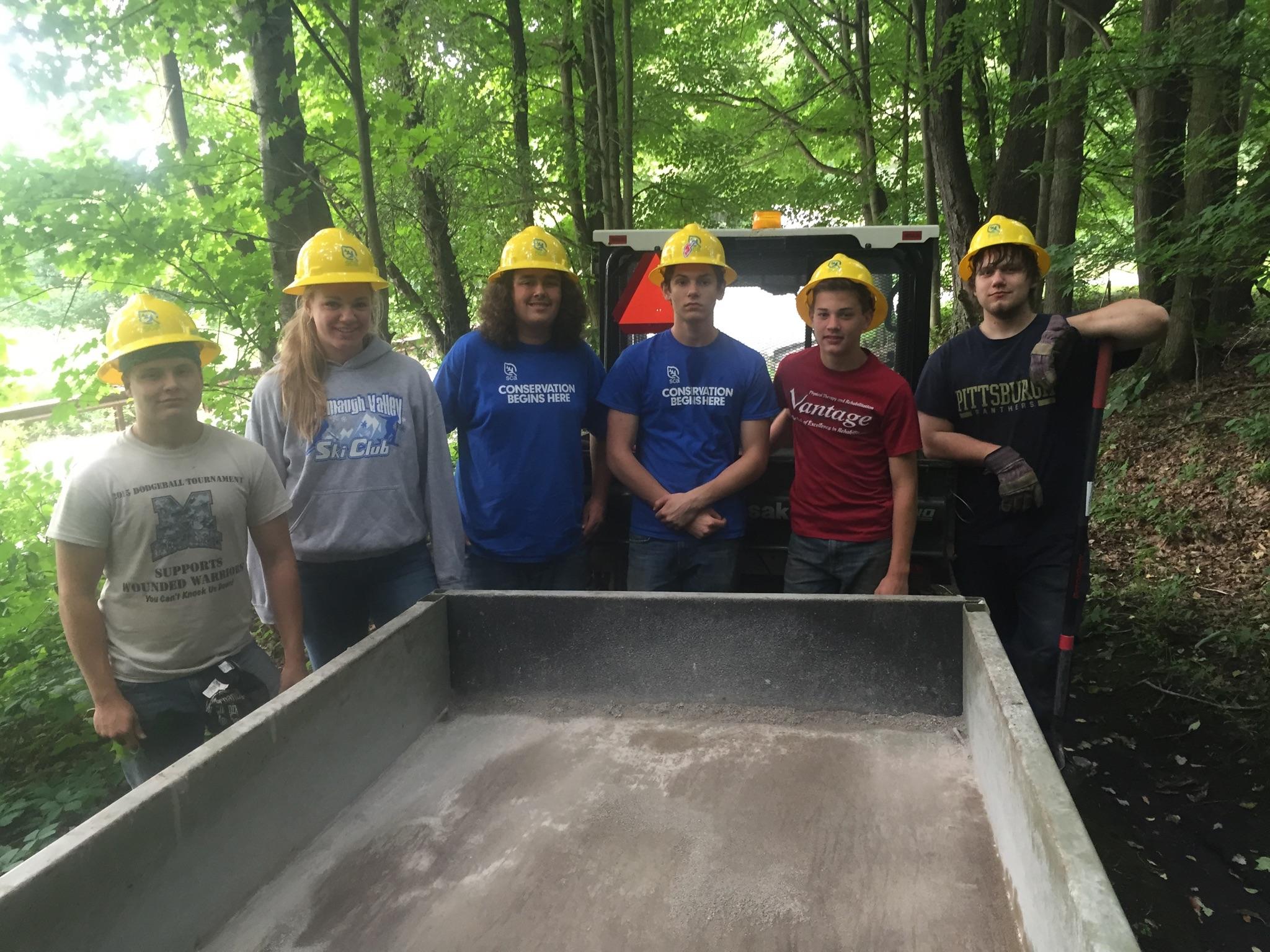 Six youth wearing work clothes and hardhats