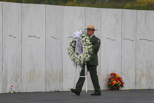 A park ranger carrying a wreath by the Wall of Names.