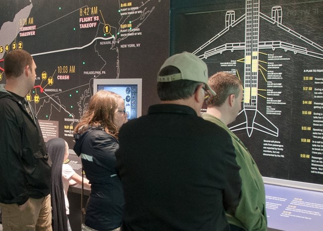 Visitor standing in front of exhibit wall with outline of a commercial airplane.