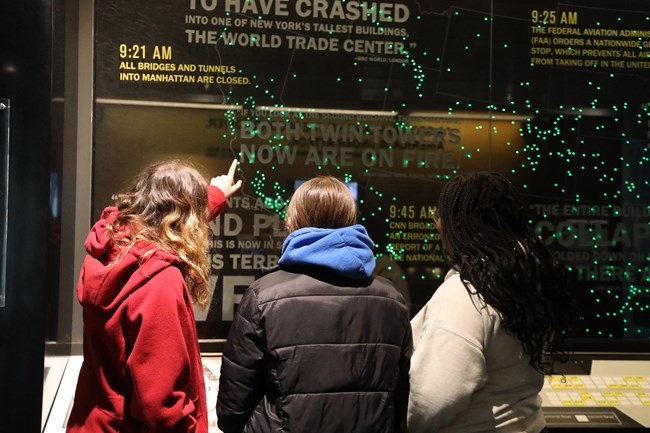 Visitors point to a map inside the Visitor Center that has several dots on it to represent the planes in the sky on September 11, 2001.