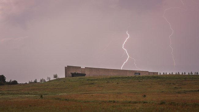 Cloud to ground lightning striking behind the visitor center lighting up the dark sky