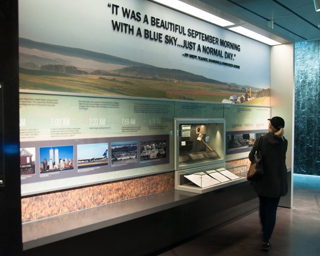 Visitor standing in front of exhibit wall describing the beginning of September 11, 2001