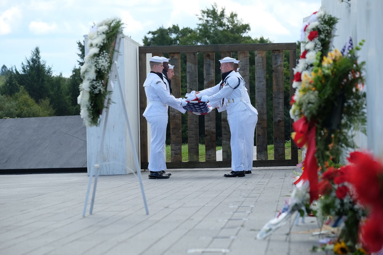 Sailors folding a flag.