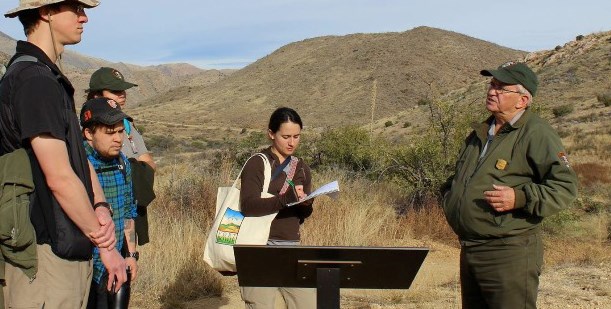 A park ranger talks to a group in the low hills of Apache Pass