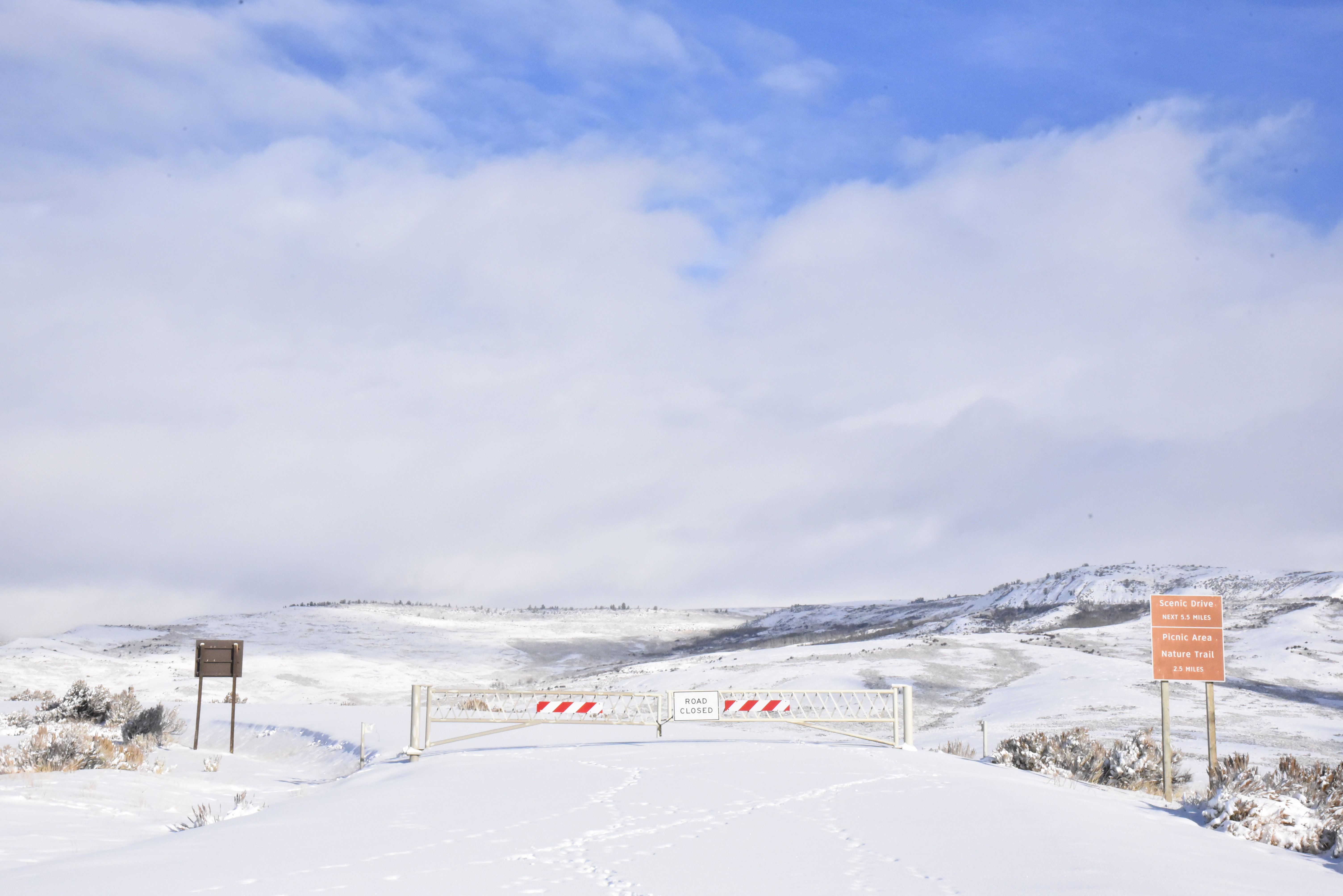 snow covered road blocked by gate