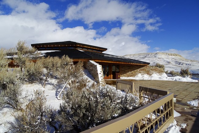 The visitor center on the left with Fossil Butte visible behind to the right. Both are dusted with snow.