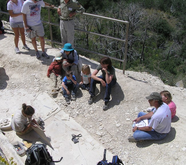 A person in uniform shows a rock to a group of people